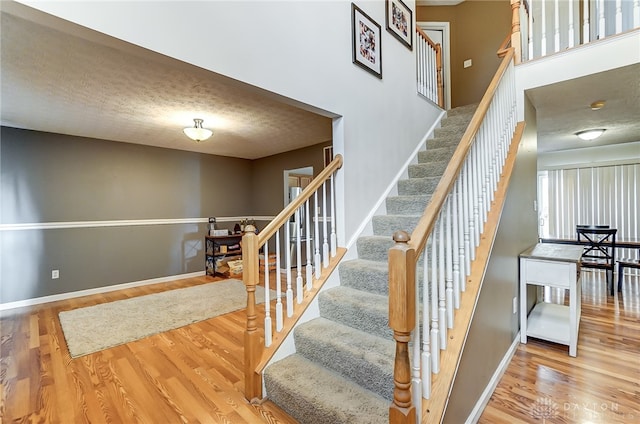 stairway with hardwood / wood-style floors and a textured ceiling