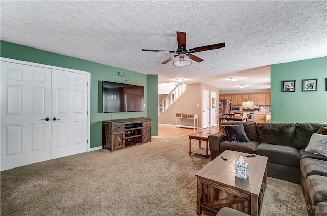 living room with light carpet, ceiling fan, and a textured ceiling