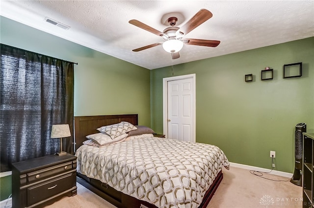 carpeted bedroom with ceiling fan and a textured ceiling