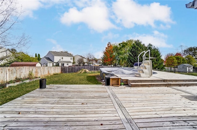 dock area featuring a jacuzzi, a lawn, and a wooden deck