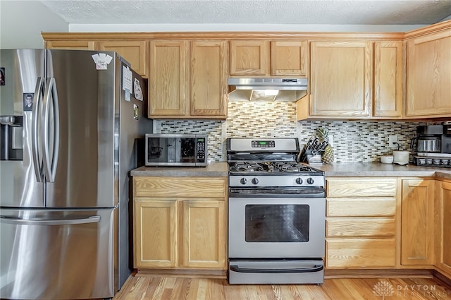 kitchen featuring light brown cabinets, backsplash, appliances with stainless steel finishes, and light hardwood / wood-style flooring