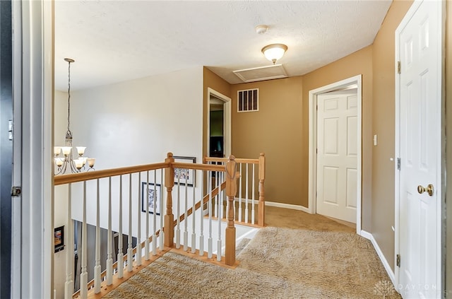 corridor with a textured ceiling and light colored carpet