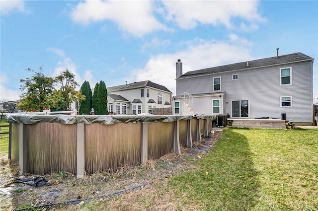 rear view of house featuring central AC unit and a yard