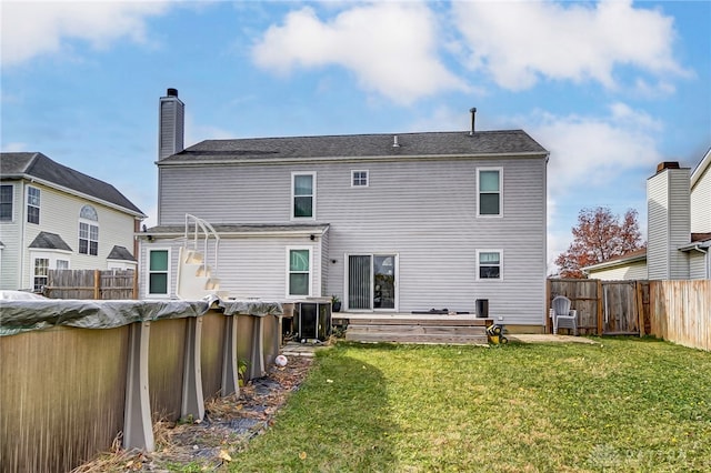 rear view of house featuring a yard and central air condition unit