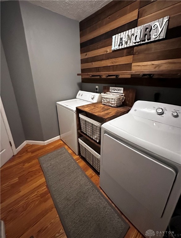 laundry area featuring dark hardwood / wood-style flooring, a textured ceiling, and washer and clothes dryer