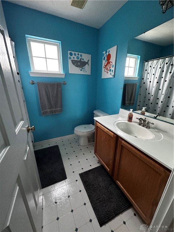 bathroom with a shower with curtain, vanity, a textured ceiling, and toilet