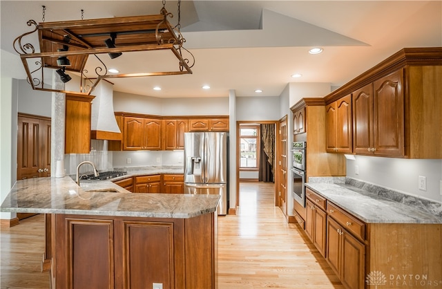 kitchen with sink, kitchen peninsula, stainless steel appliances, custom exhaust hood, and light hardwood / wood-style flooring