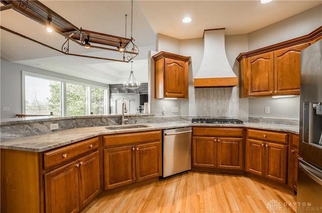 kitchen with custom range hood, light hardwood / wood-style flooring, appliances with stainless steel finishes, and sink