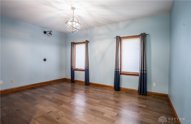 unfurnished room with a notable chandelier, plenty of natural light, and hardwood / wood-style floors