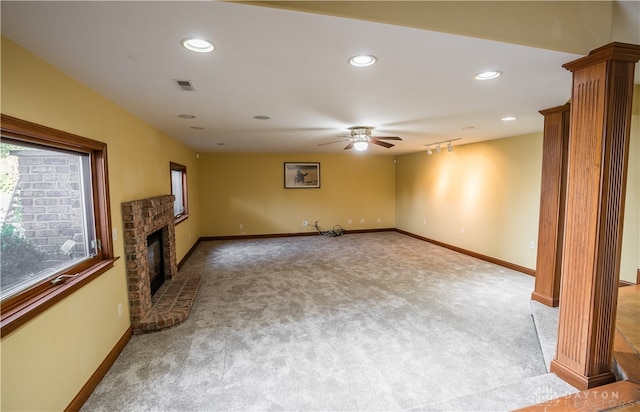 unfurnished living room featuring ornate columns, ceiling fan, a fireplace, and light colored carpet