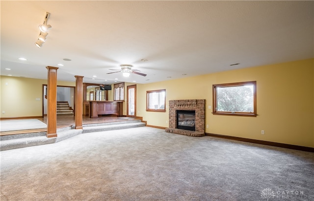 unfurnished living room featuring carpet floors, a fireplace, and decorative columns