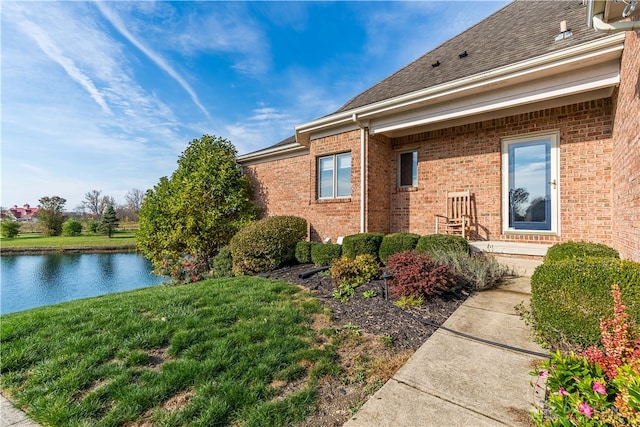 view of side of home featuring a yard and a water view