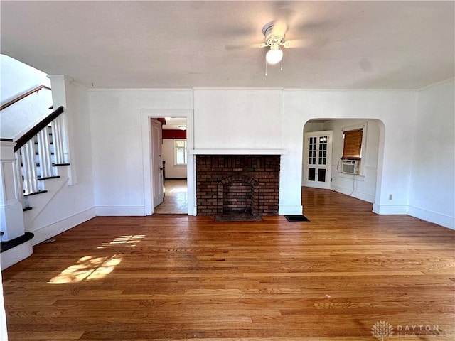 unfurnished living room with hardwood / wood-style floors, ceiling fan, cooling unit, and a brick fireplace