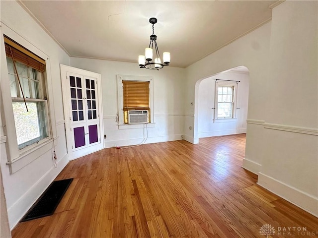 unfurnished dining area with hardwood / wood-style flooring, cooling unit, crown molding, and a chandelier