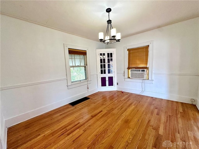 unfurnished dining area with hardwood / wood-style floors, cooling unit, a chandelier, and french doors