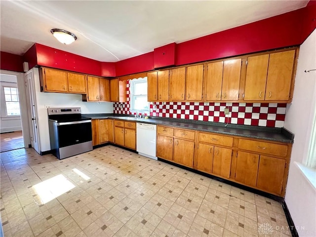 kitchen with a wealth of natural light, sink, stainless steel range with electric cooktop, and white dishwasher