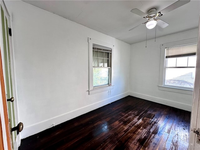 spare room with dark wood-type flooring, ceiling fan, and a healthy amount of sunlight