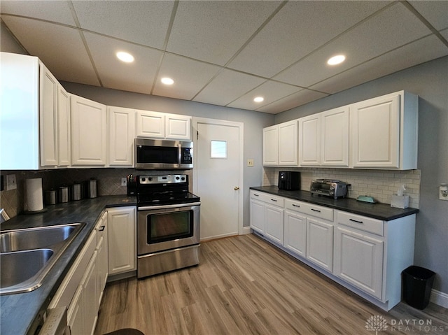 kitchen featuring tasteful backsplash, white cabinetry, sink, light hardwood / wood-style floors, and stainless steel appliances