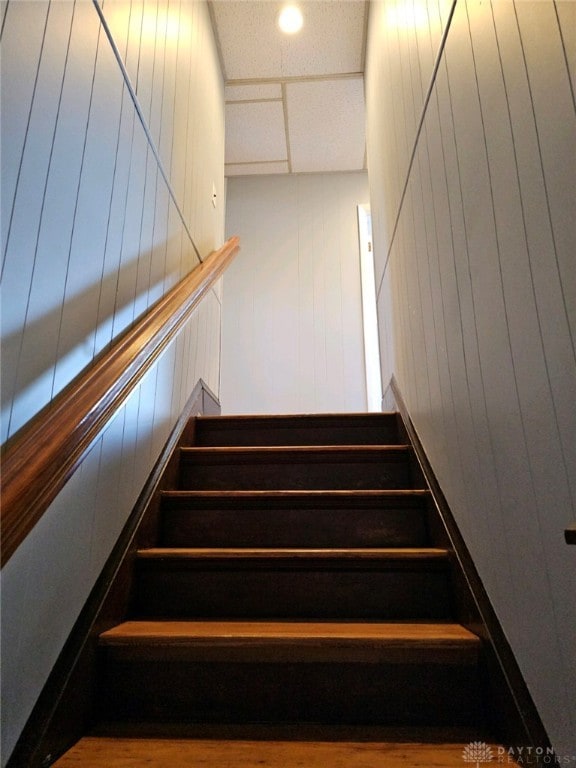 stairway featuring wooden walls