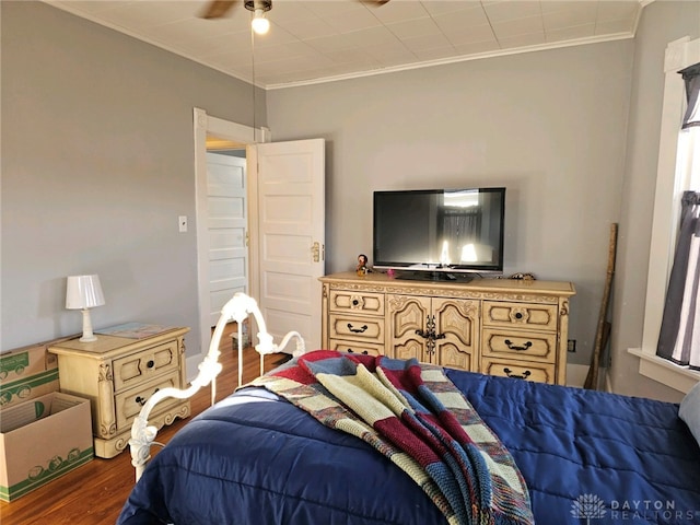 bedroom with crown molding, dark wood-type flooring, and ceiling fan