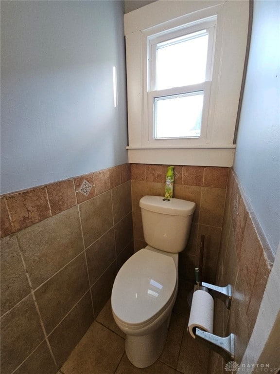 bathroom with toilet, tile walls, and tile patterned flooring