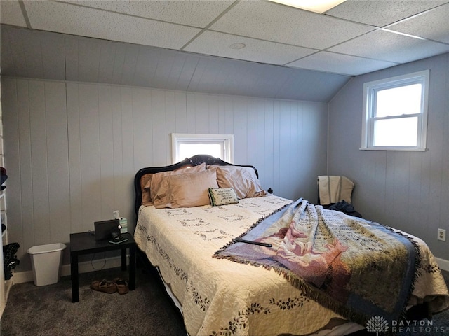 bedroom featuring carpet flooring, a drop ceiling, and wooden walls