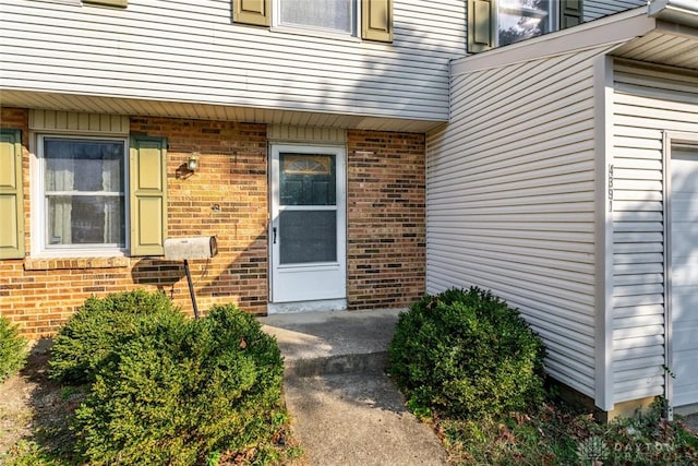 property entrance with brick siding and a garage