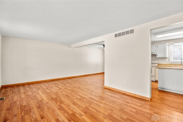 unfurnished living room featuring light wood-style flooring, visible vents, and baseboards