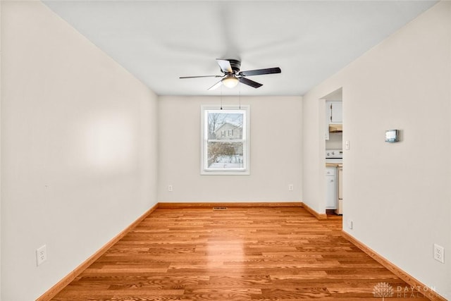 spare room featuring baseboards, a ceiling fan, and light wood-style floors