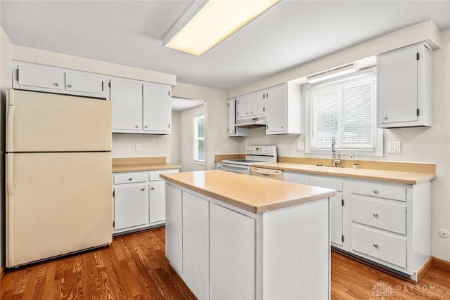 kitchen with light countertops, a center island, white cabinets, and white appliances