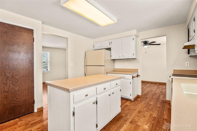 kitchen with freestanding refrigerator, light wood-style flooring, a kitchen island, white cabinetry, and light countertops