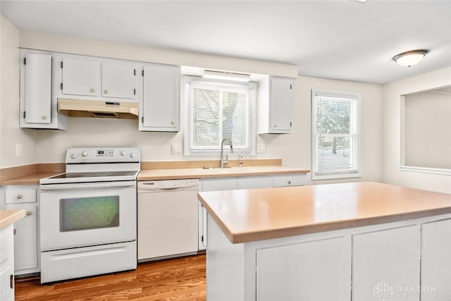 kitchen with white cabinetry, a sink, light countertops, under cabinet range hood, and white appliances