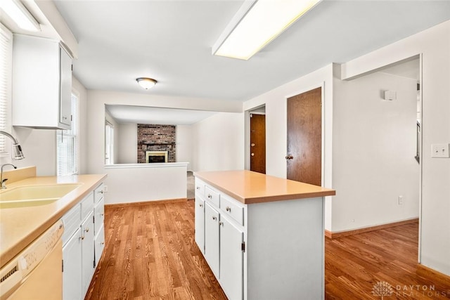 kitchen with light countertops, white cabinets, white dishwasher, and a sink