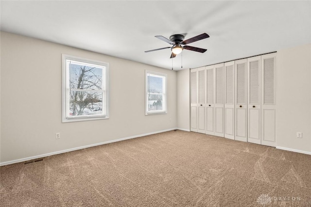 unfurnished bedroom featuring baseboards, ceiling fan, visible vents, and carpet floors