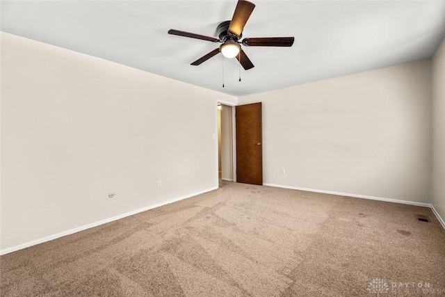 empty room with carpet flooring, baseboards, a ceiling fan, and visible vents