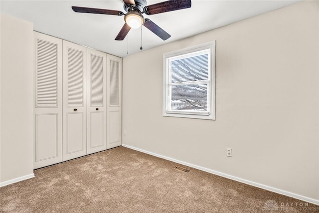 unfurnished bedroom with ceiling fan, baseboards, visible vents, light colored carpet, and a closet