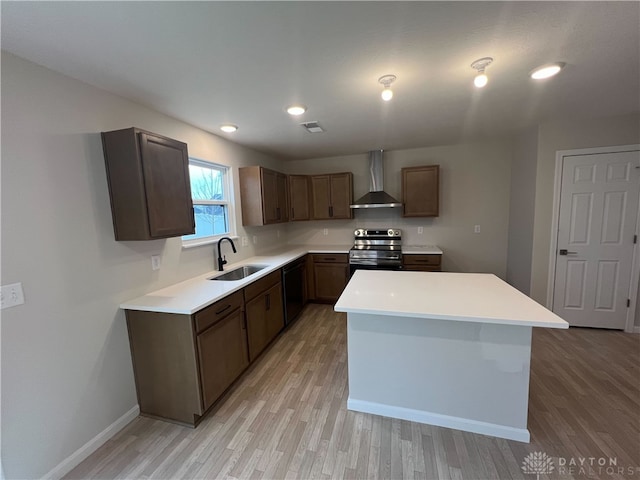 kitchen featuring electric stove, sink, wall chimney exhaust hood, light wood-type flooring, and a kitchen island