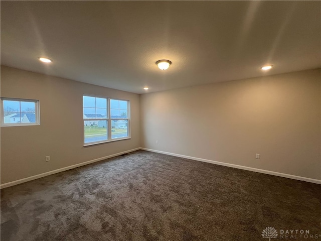 spare room with dark carpet