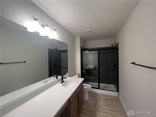 bathroom featuring a textured ceiling, hardwood / wood-style flooring, toilet, and walk in shower