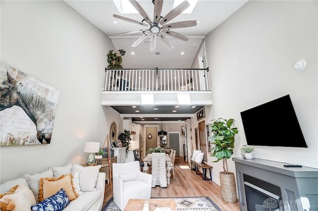 living room with ceiling fan, light hardwood / wood-style floors, a fireplace, and high vaulted ceiling