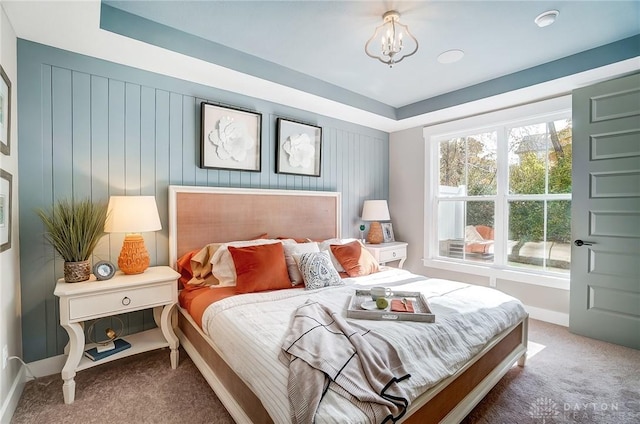 bedroom featuring a tray ceiling, carpet, and a notable chandelier