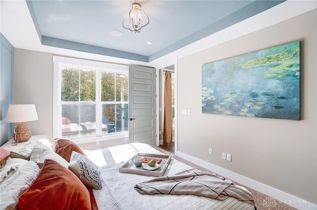 bedroom featuring carpet flooring, a raised ceiling, and an inviting chandelier