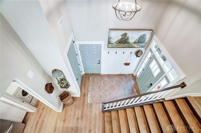 entryway featuring wood-type flooring, a high ceiling, and a chandelier