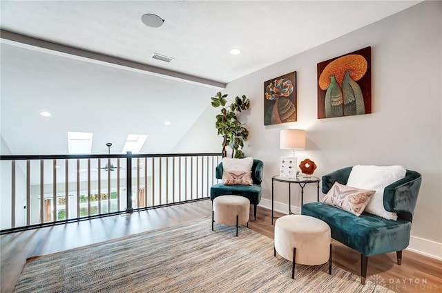 living area with wood-type flooring and vaulted ceiling with skylight