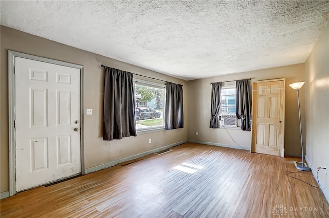 entryway with light hardwood / wood-style floors, cooling unit, a textured ceiling, and a wealth of natural light