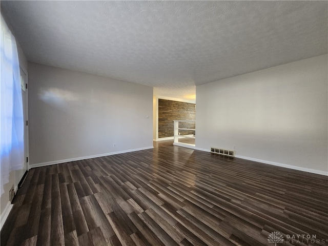 unfurnished room featuring a textured ceiling and dark hardwood / wood-style floors