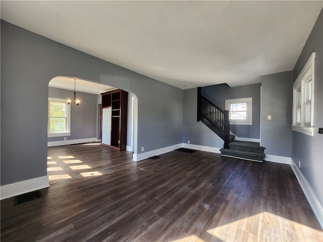 unfurnished living room featuring a notable chandelier and dark hardwood / wood-style flooring