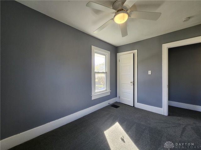 unfurnished bedroom with ceiling fan and dark colored carpet