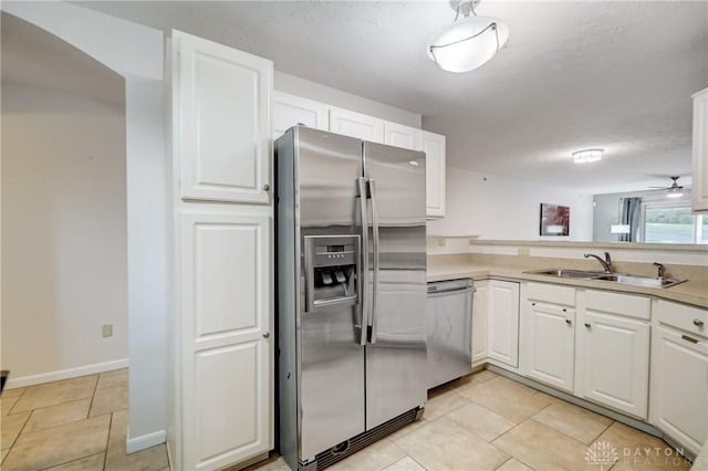 kitchen featuring ceiling fan, sink, white cabinets, light tile patterned floors, and stainless steel appliances