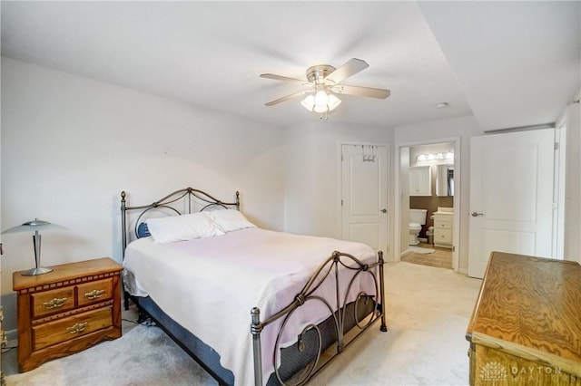 bedroom with ceiling fan, ensuite bathroom, and light colored carpet